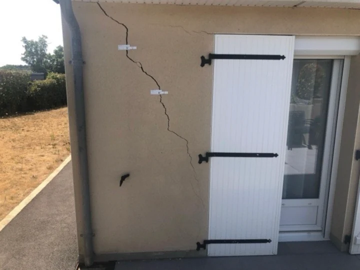 Fissure en façade près d’une fenêtre à volets